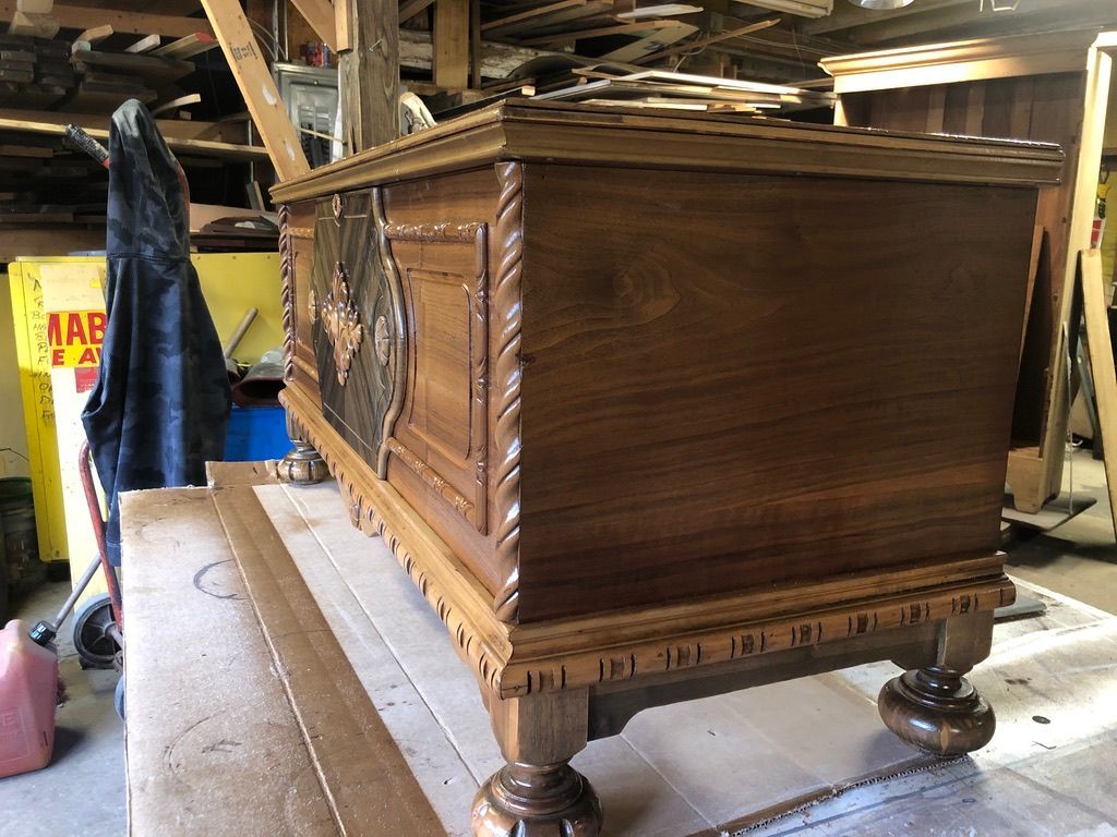 Wooden chest on a workbench with ornate carvings and raised feet.