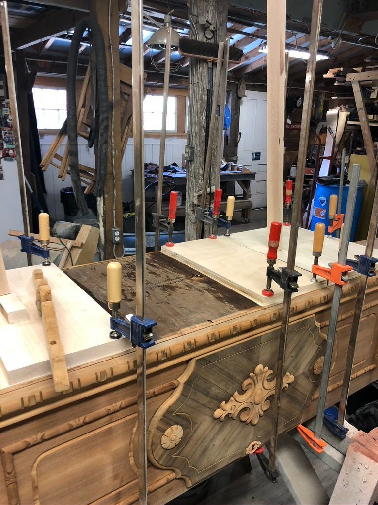 Wooden furniture being repaired with clamps in a workshop.
