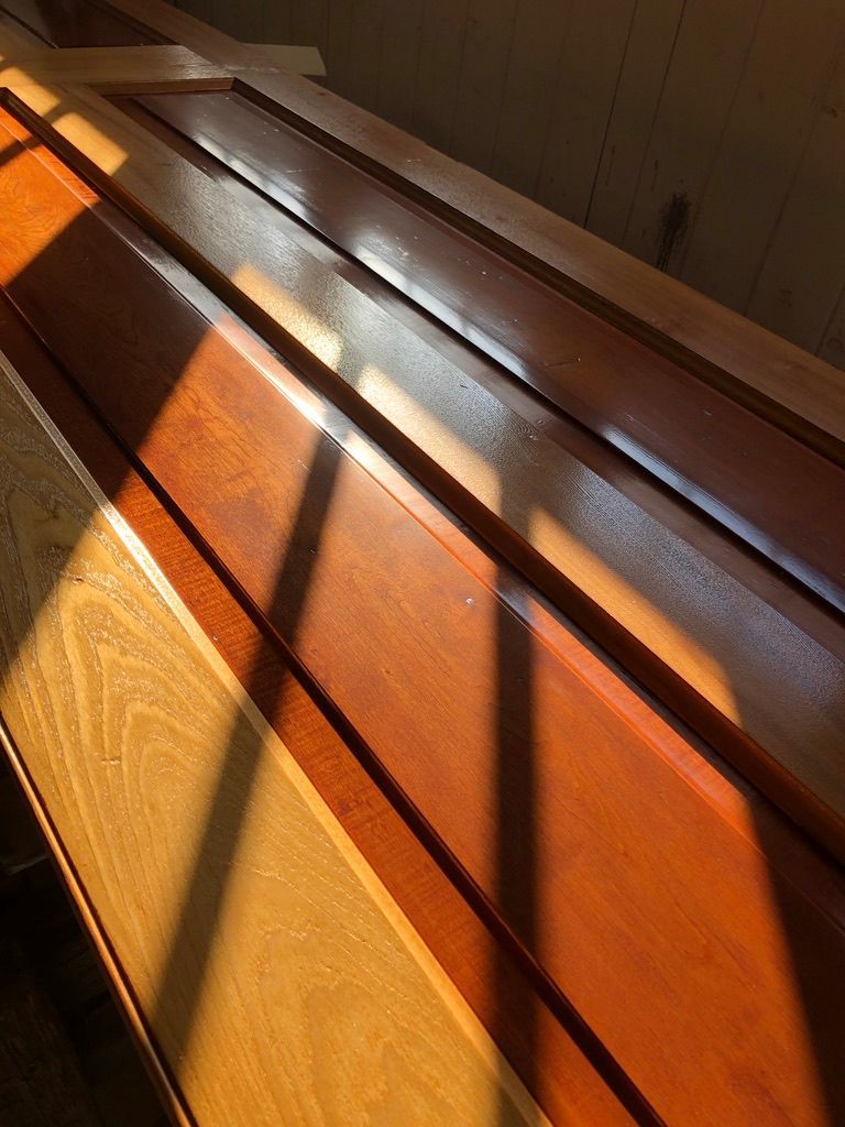 Wooden planks, varying shades of brown, bathed in sunlight, resting in a corner.