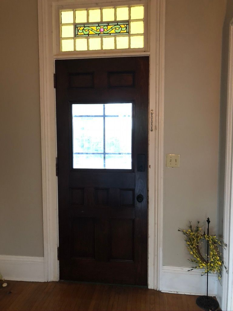 Dark wooden door with glass panel and transom window, surrounded by white trim.