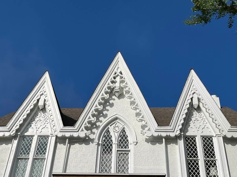 White building with three ornate pointed gables against a blue sky.