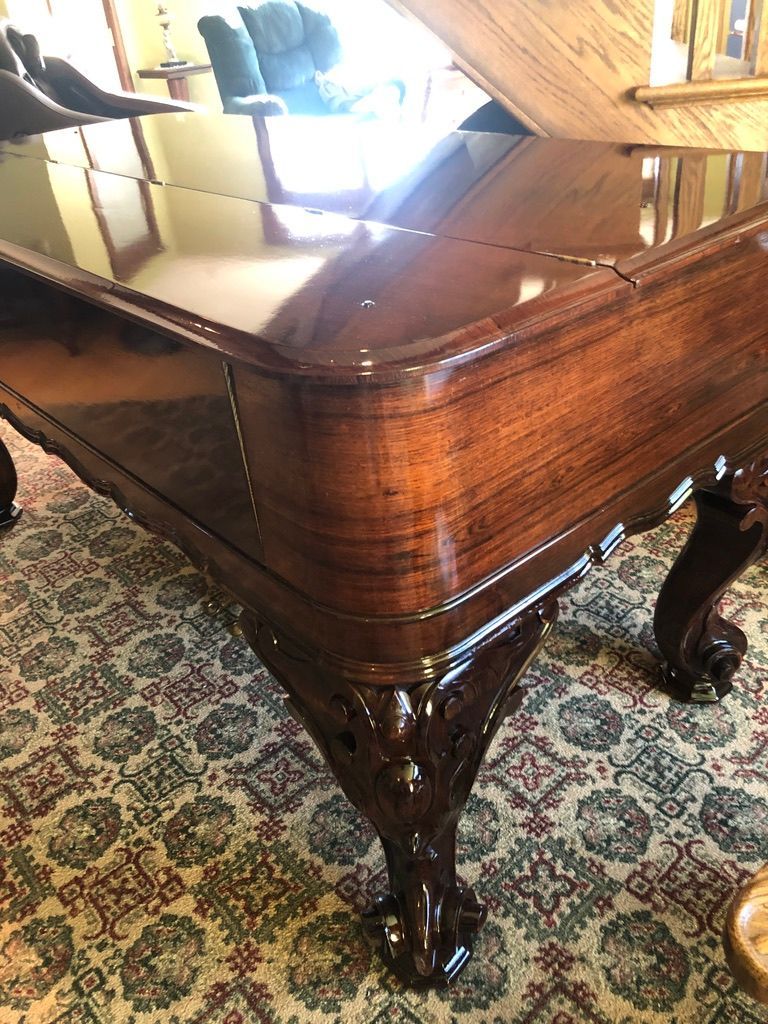 Close-up of a dark wood table with ornate carved legs and a reflective, shiny top.