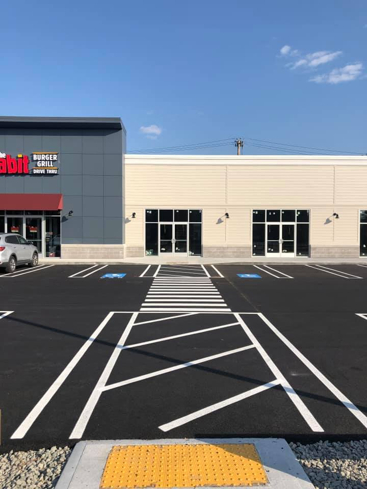 Accessible parking spaces and crosswalk in front of a storefront on a sunny day
