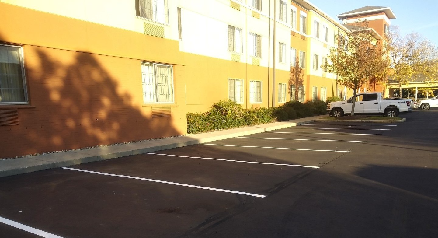 Apartment building beside empty parking lot with marked spaces in bright sunlight