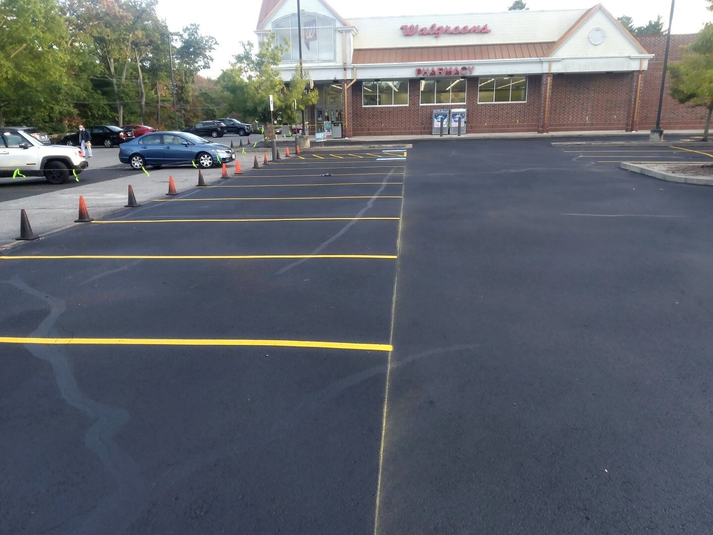 Empty parking lot with fresh yellow lines outside a brick storefront building.