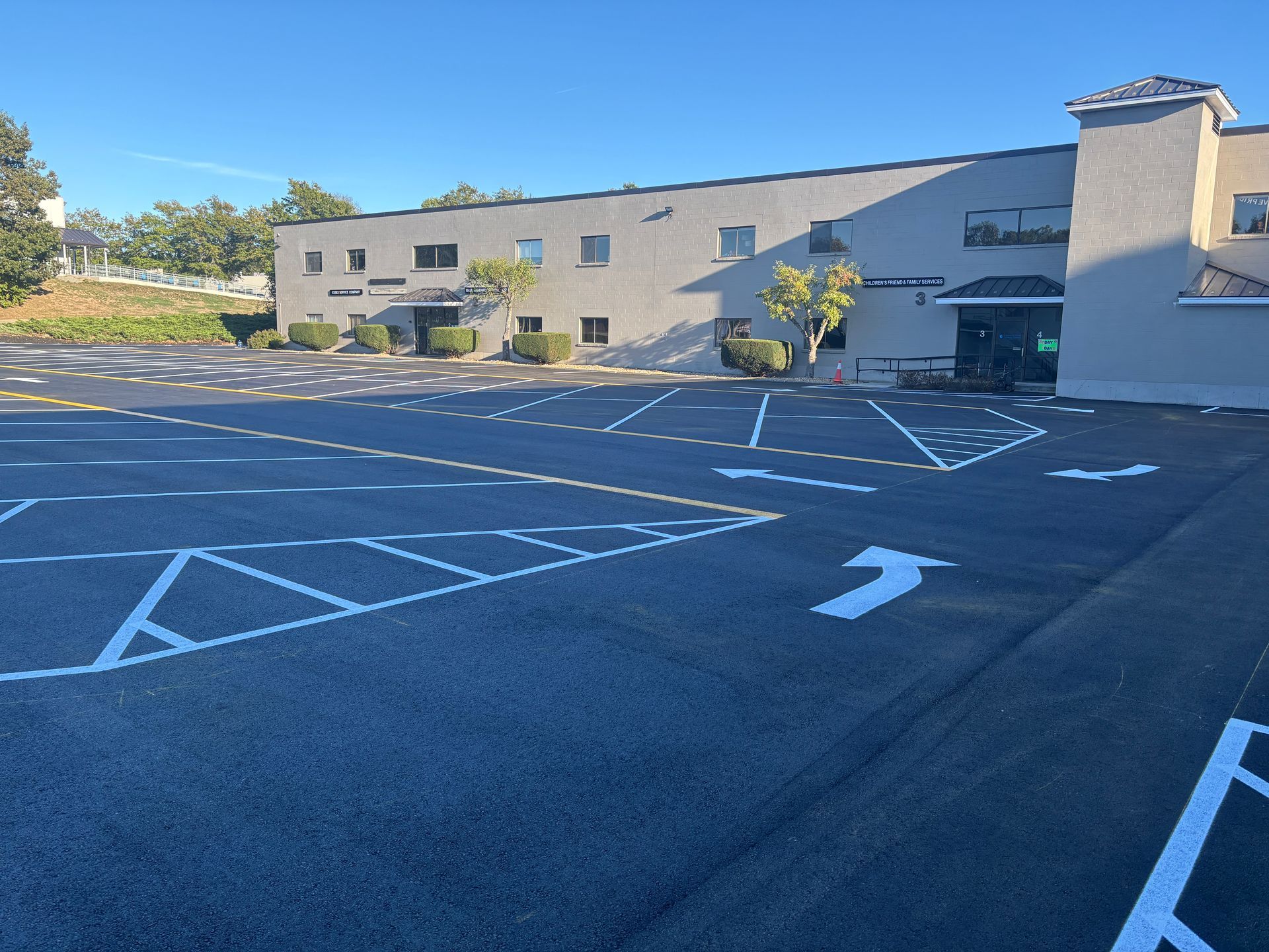 Empty parking lot with accessible parking spaces marked in white outside a beige building.