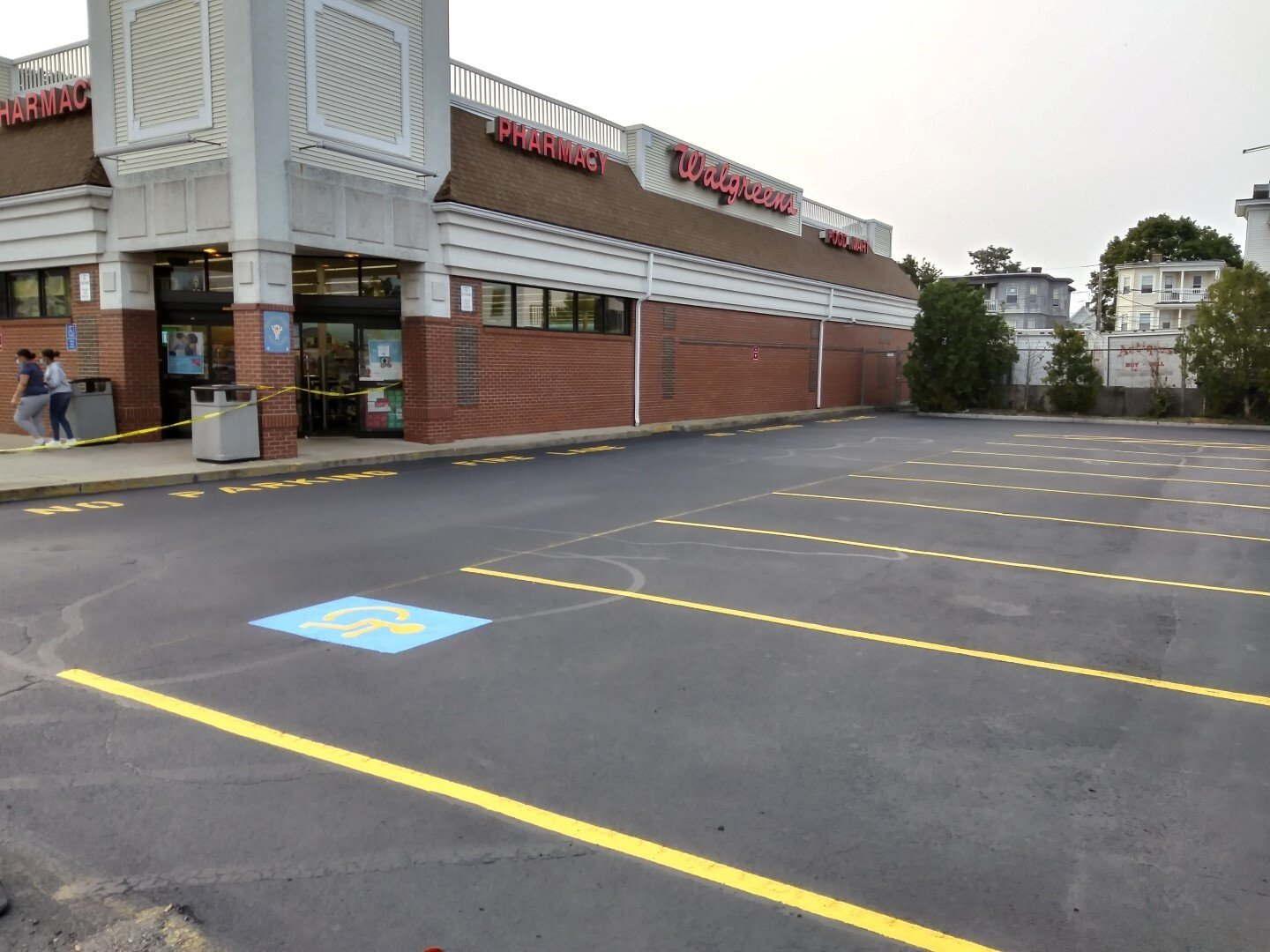 Empty parking lot beside a brick commercial building with yellow lines and accessible parking spaces