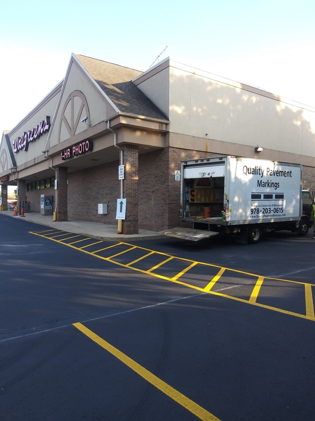 Grocery store entrance with a delivery truck parked by the curb and yellow parking lines on the pavement