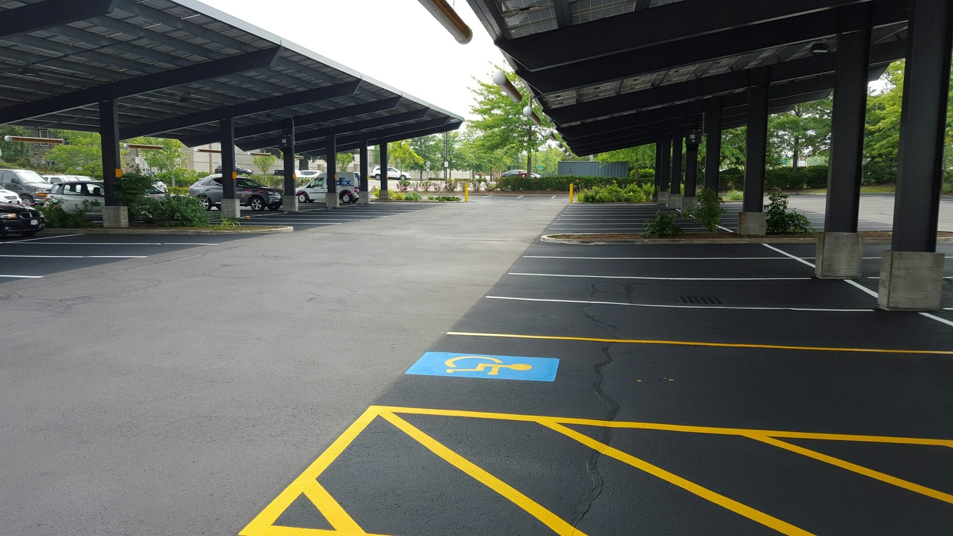Covered parking lot with empty spaces and a blue accessible parking spot marked on the pavement.