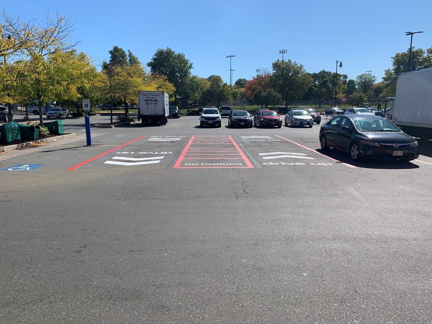 Parking lot with marked accessible spaces and several cars parked under a sunny sky