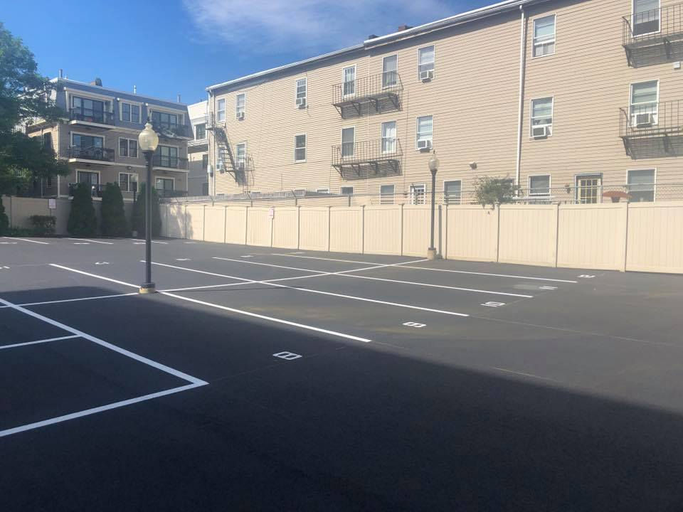 Empty outdoor parking lot beside beige apartment buildings under a clear blue sky