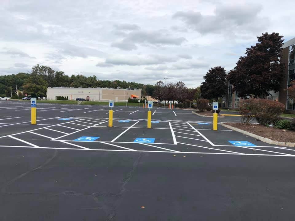 Empty accessible parking lot with blue-marked spaces, yellow bollards, and overcast sky