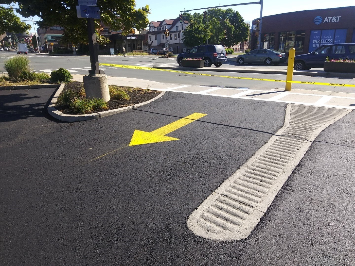 Parking lot exit with a yellow directional arrow and accessible curb ramp across the street.