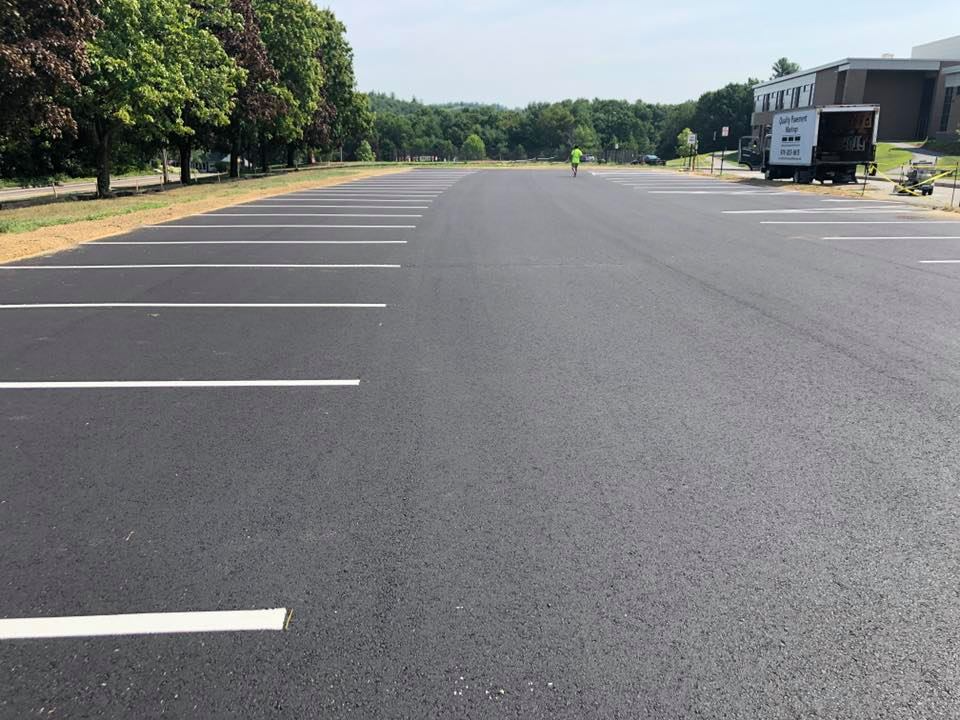 Empty parking lot with painted spaces, trees along the left, and a food truck in the distance.