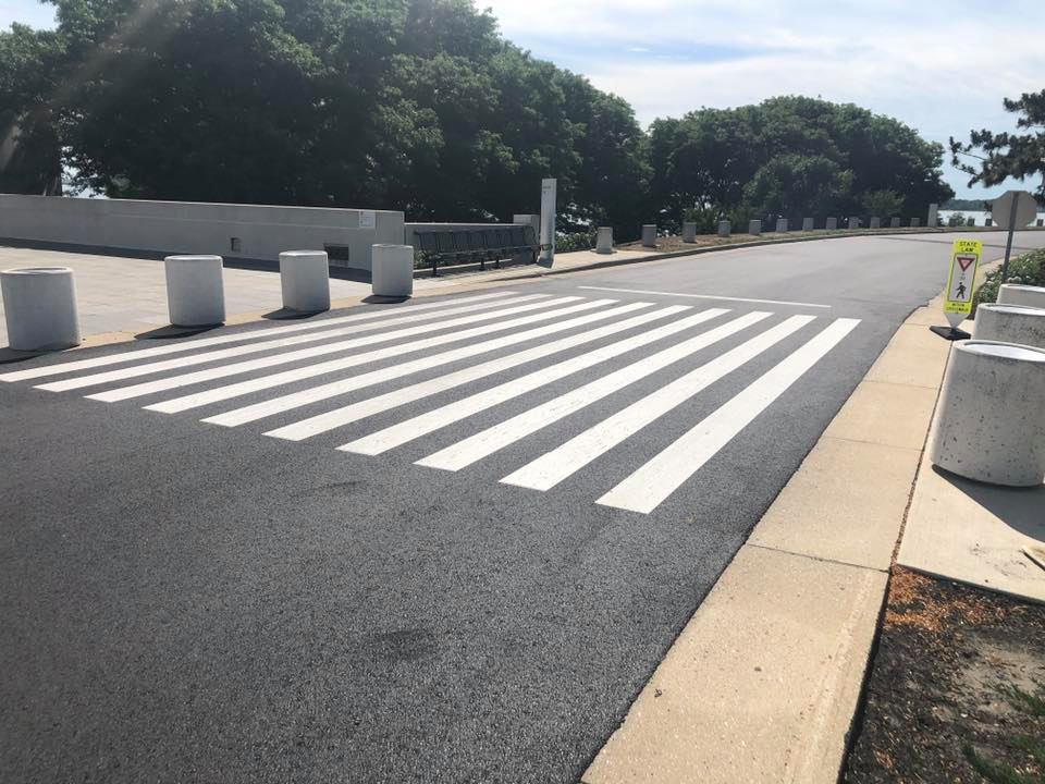 Empty pedestrian crosswalk with bold white stripes across a wide road on a sunny day