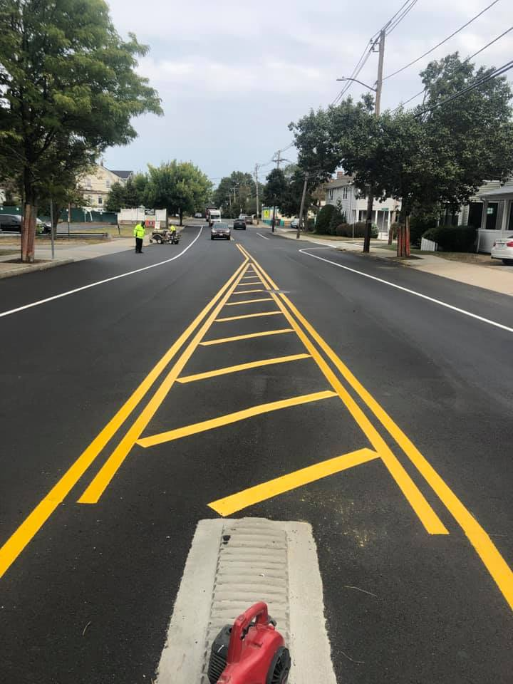 Street view of a road with yellow lane markings and a curb ramp in the foreground