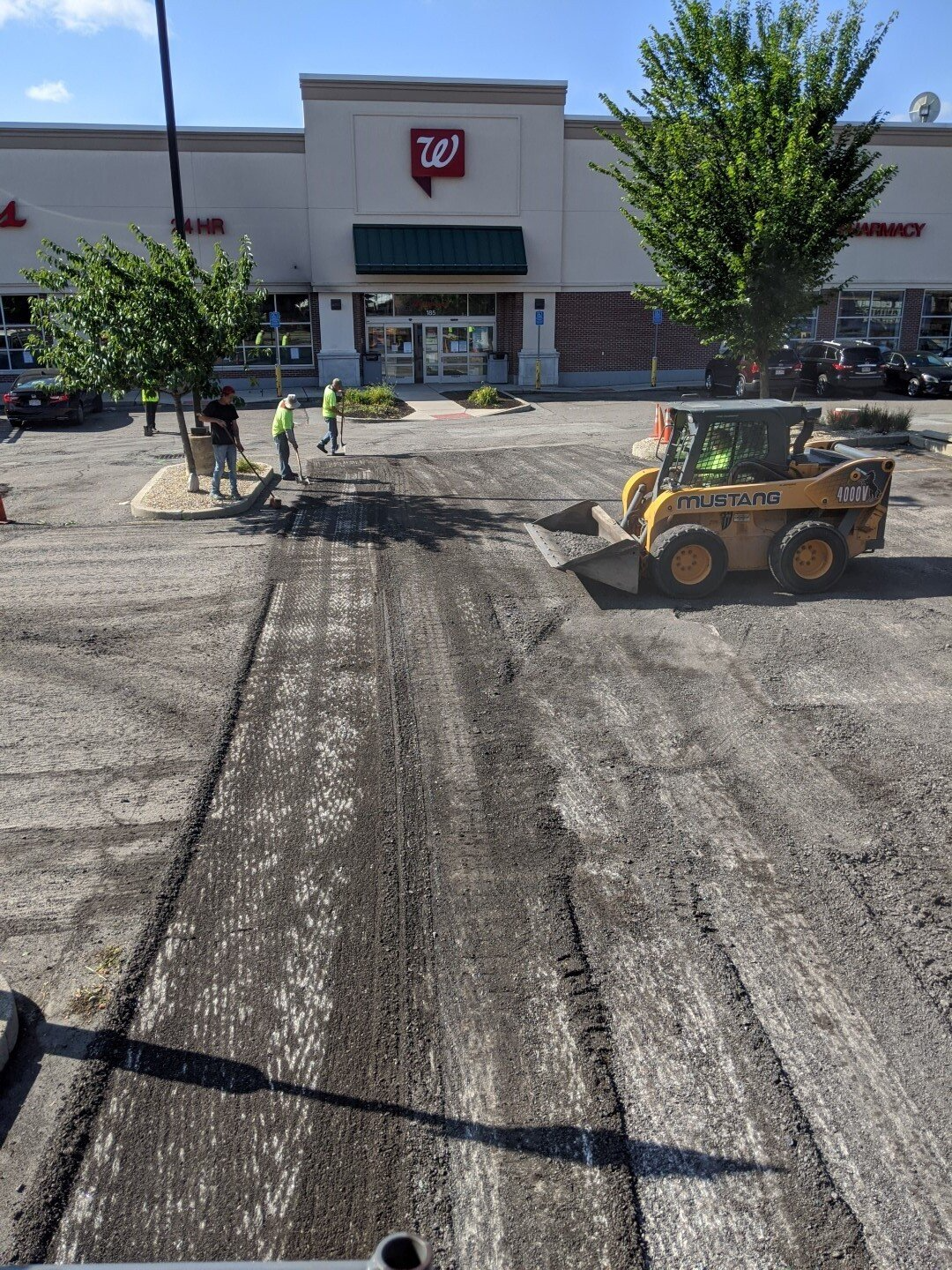 Construction workers resurfacing a parking lot outside a 7-Eleven store