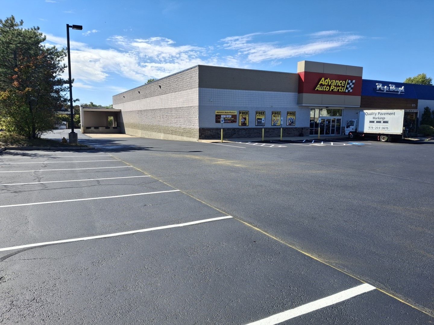 Empty parking lot outside a retail store with a red sign under a blue sky.