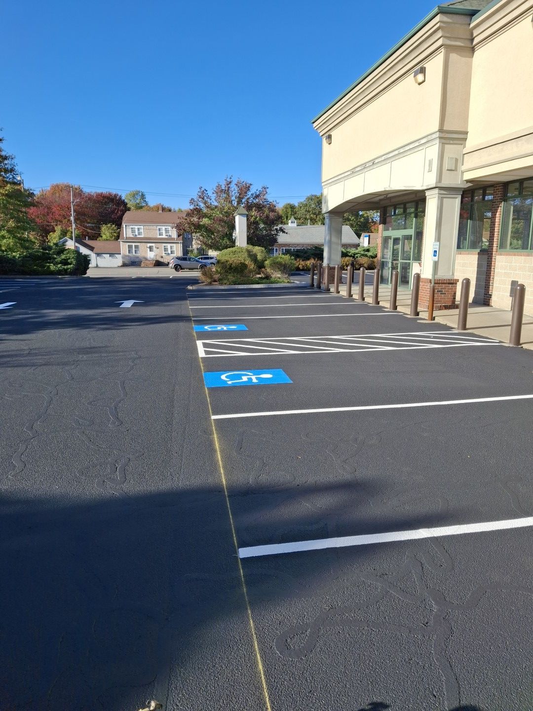 Empty accessible parking spaces outside a beige storefront on a sunny day.