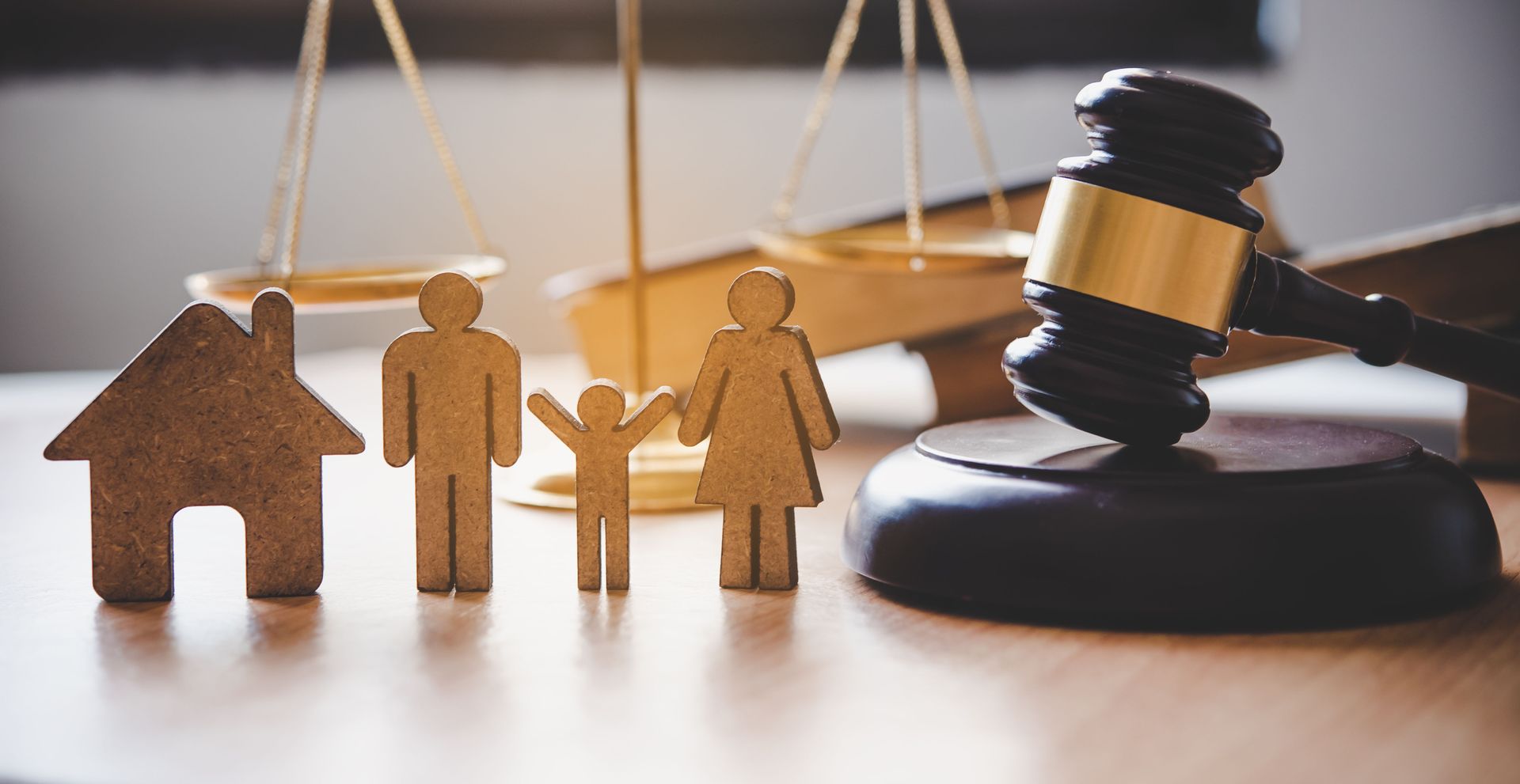 A wooden family , house , scales of justice and a judge 's gavel on a wooden table.