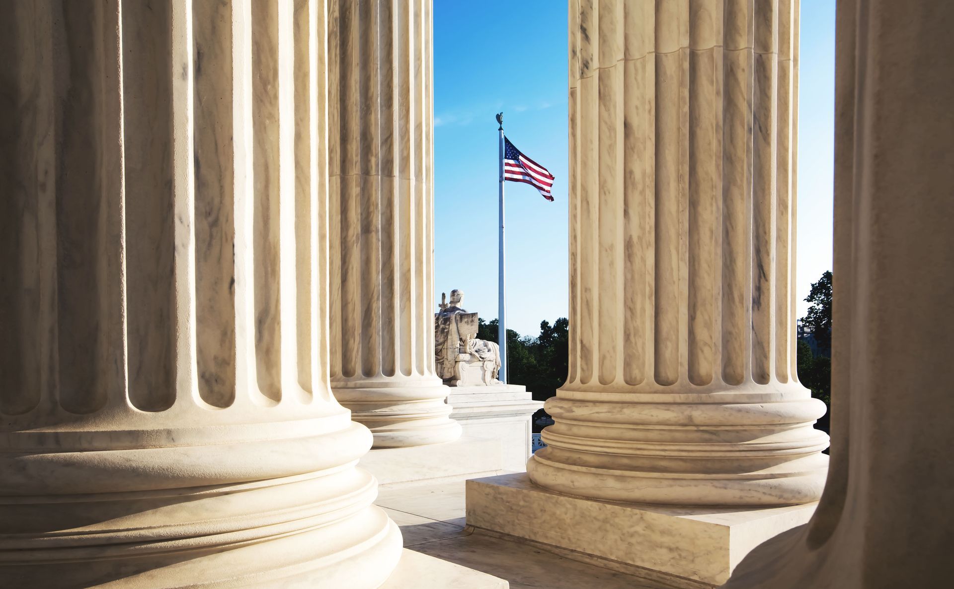 A row of columns with an american flag flying in the background.