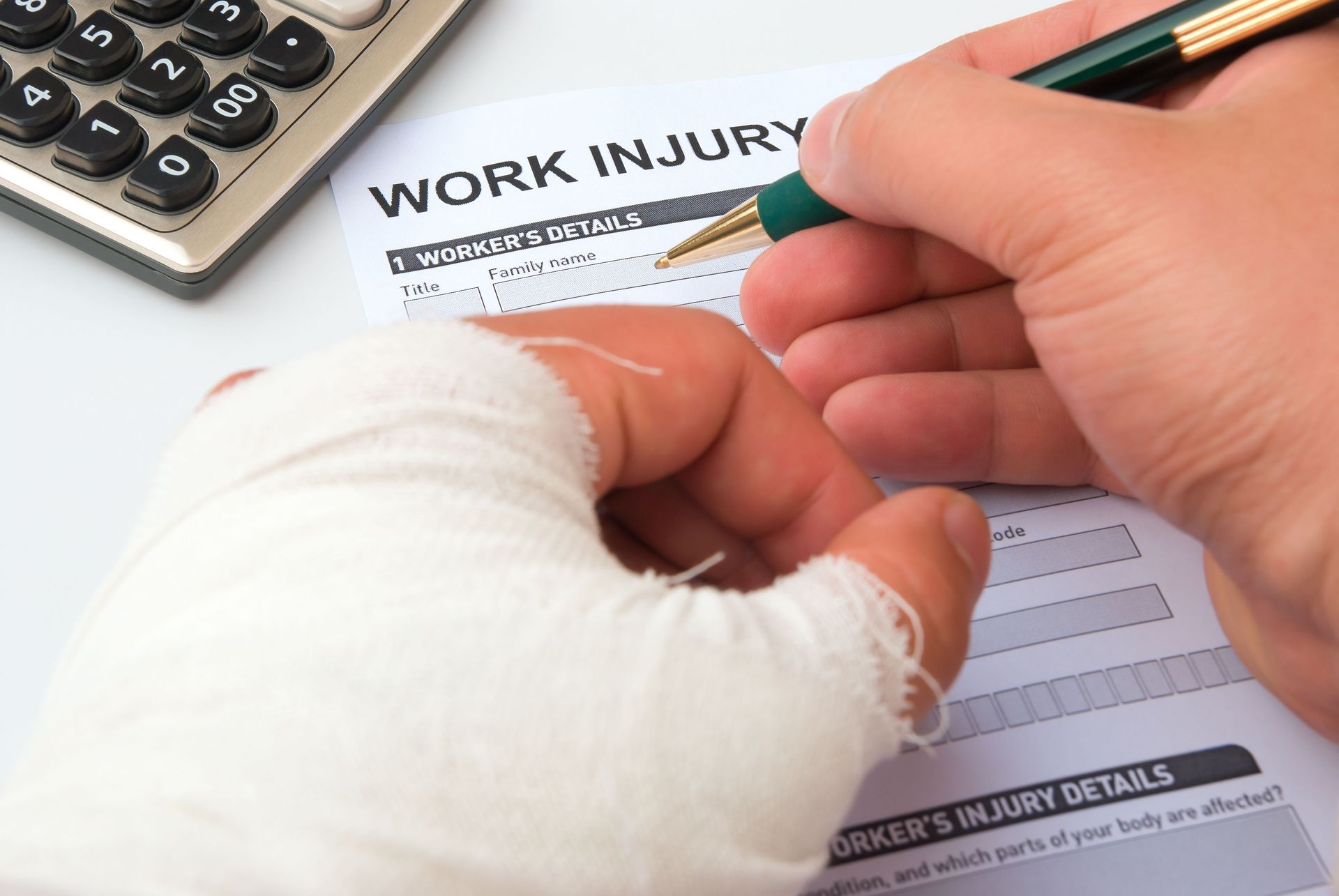 A person with a bandaged hand is filling out a work injury form.