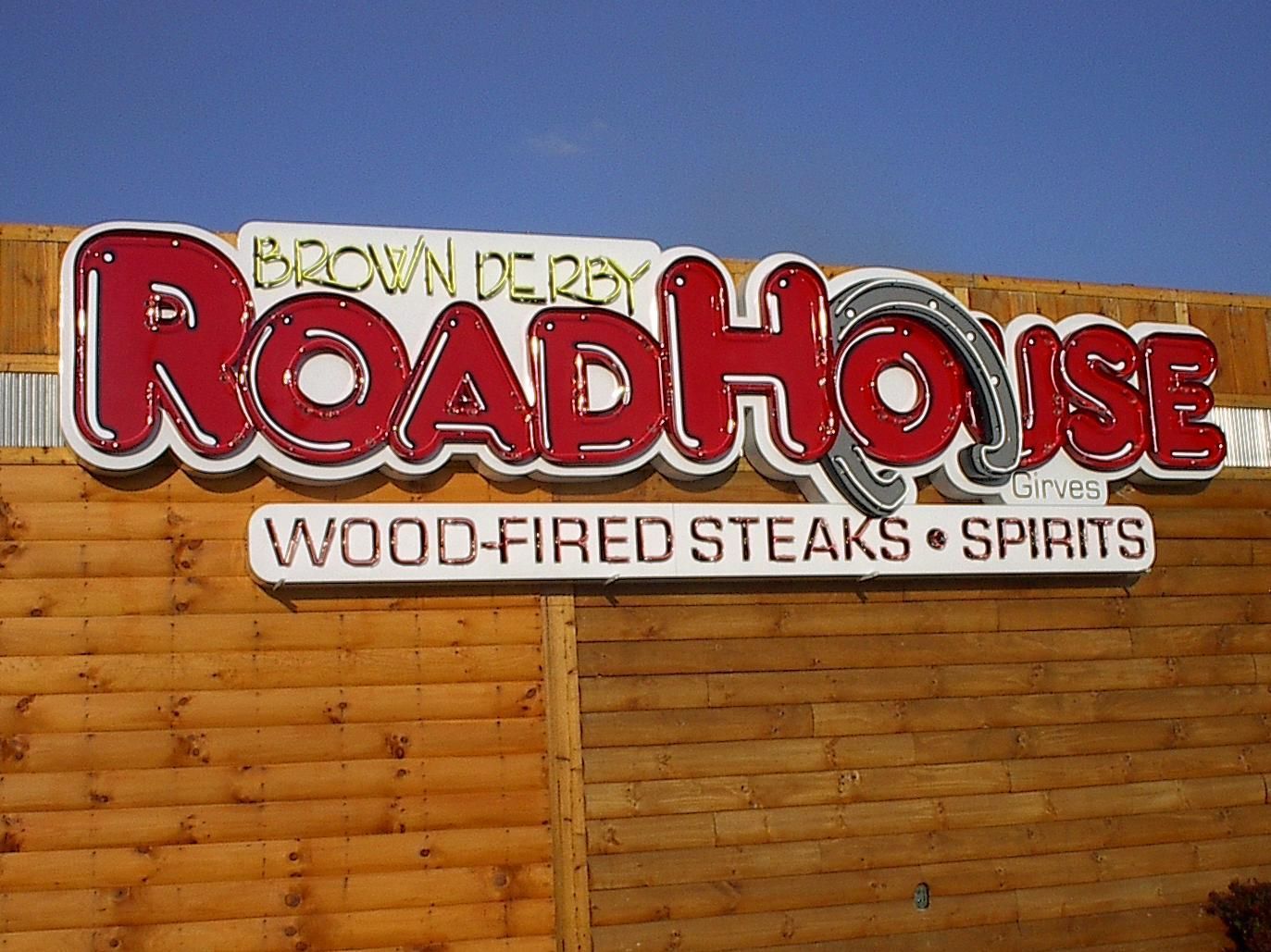 a sign for the brown derby roadhouse wood fired steaks spirits