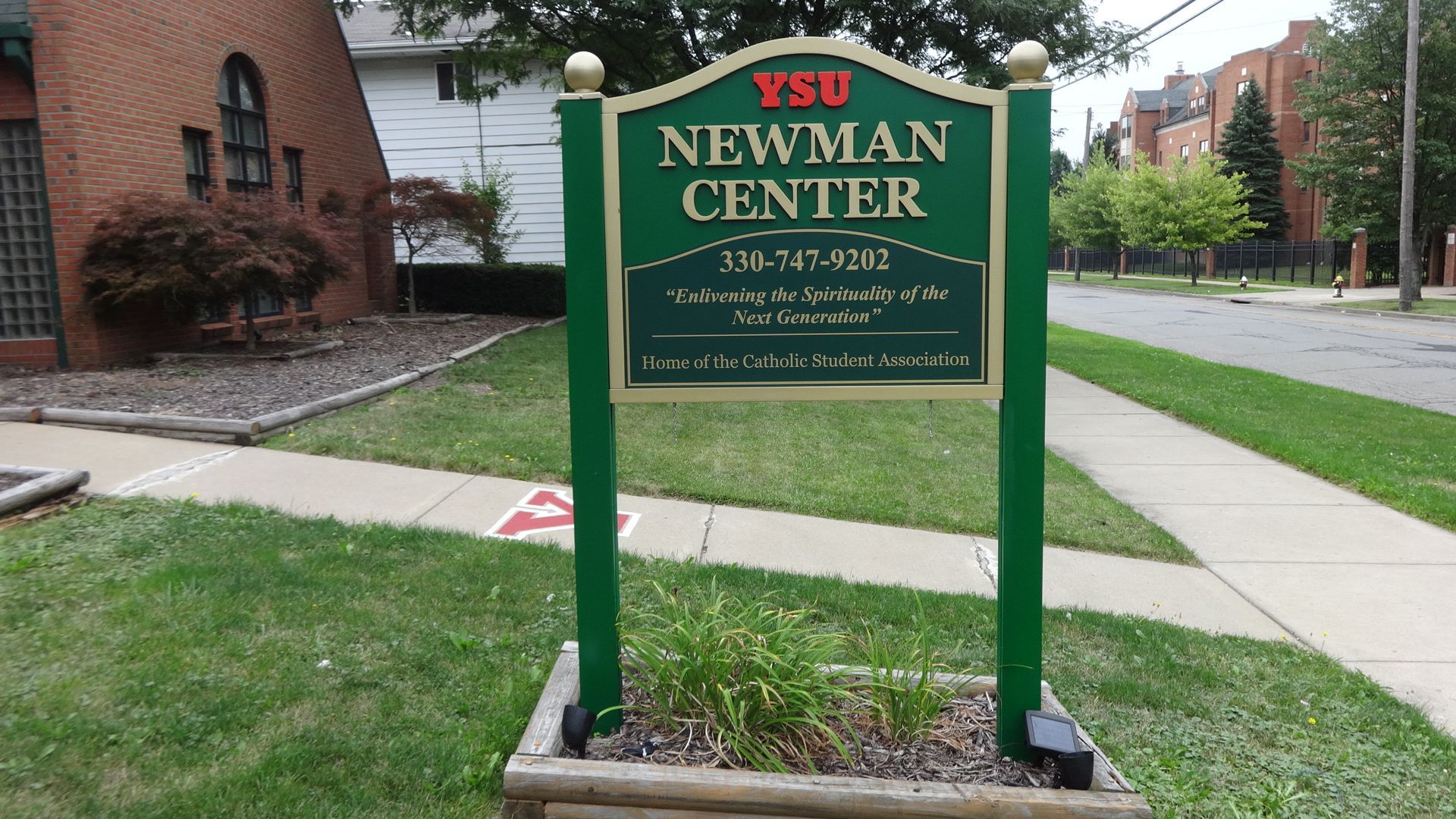 a green sign that says ysu newman center