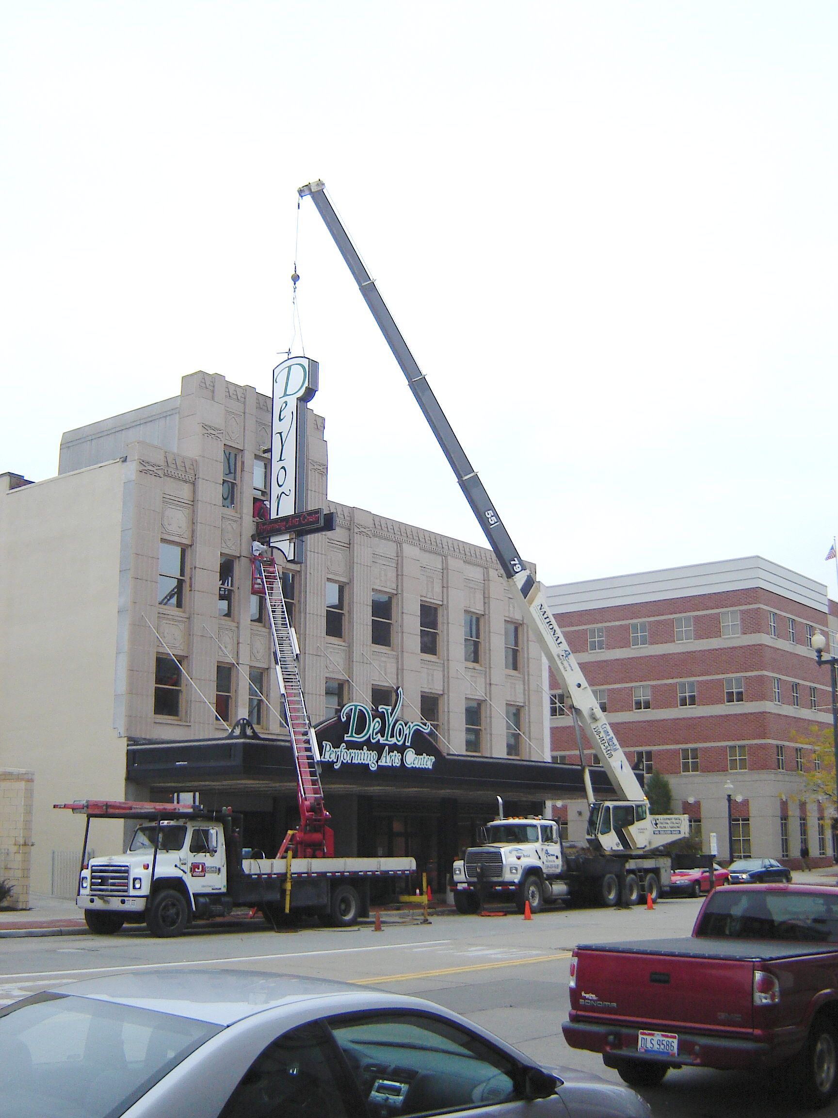 a large crane is lifting a sign in front of a building
