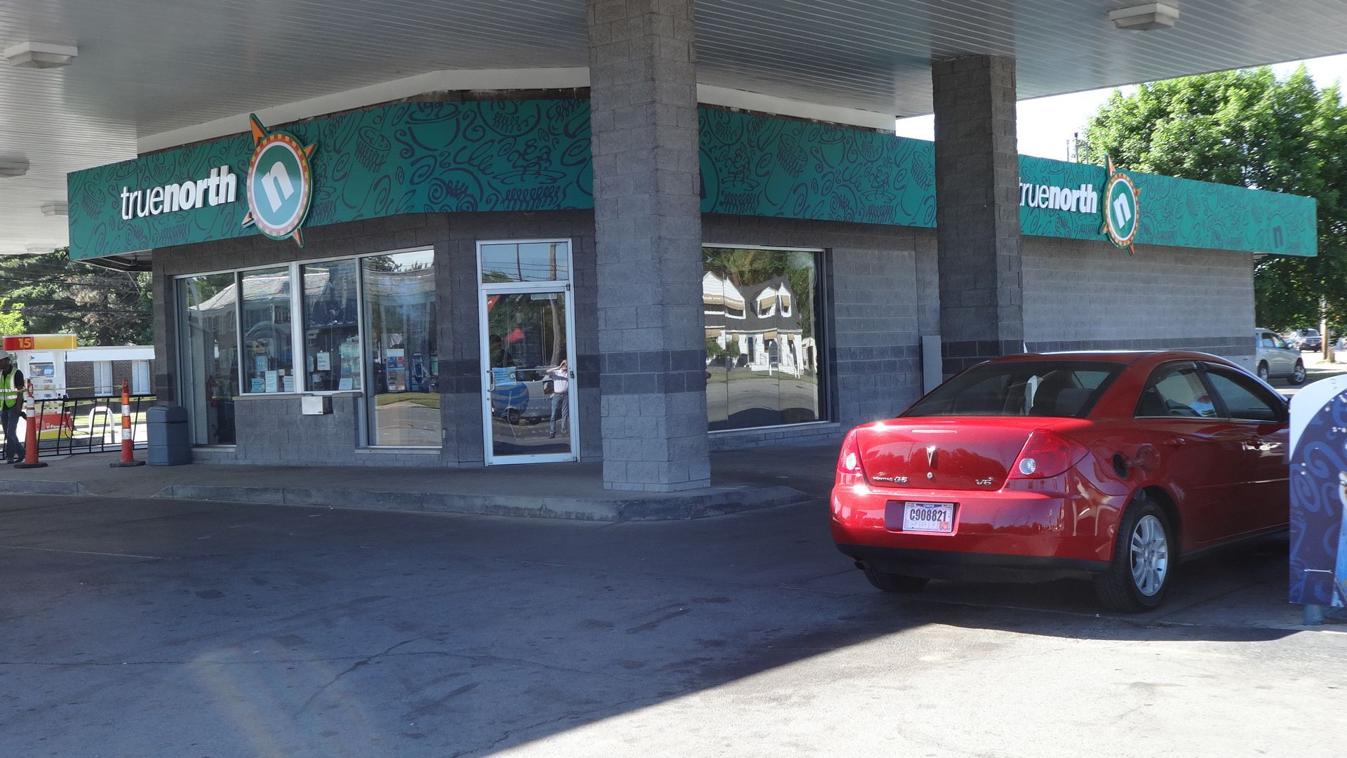 a red car is parked in front of a gas station