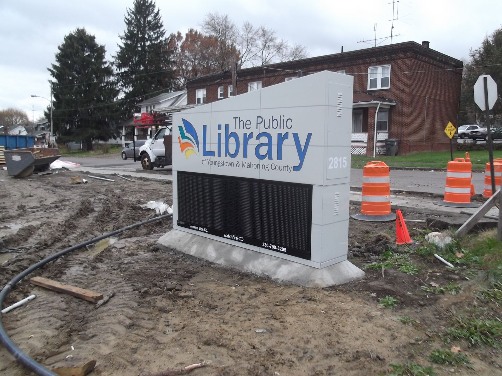 a sign for the public library is sitting in the dirt