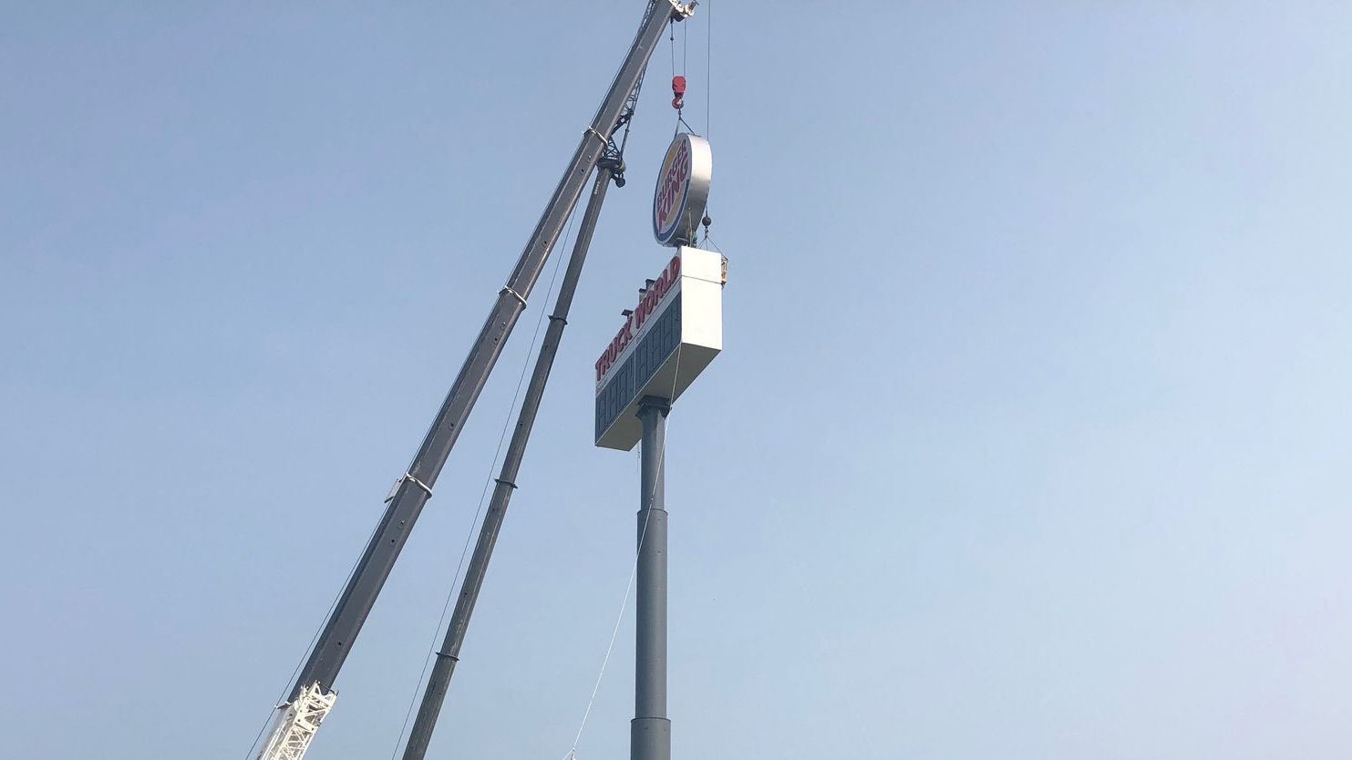 crane holding sign in air for truck stop