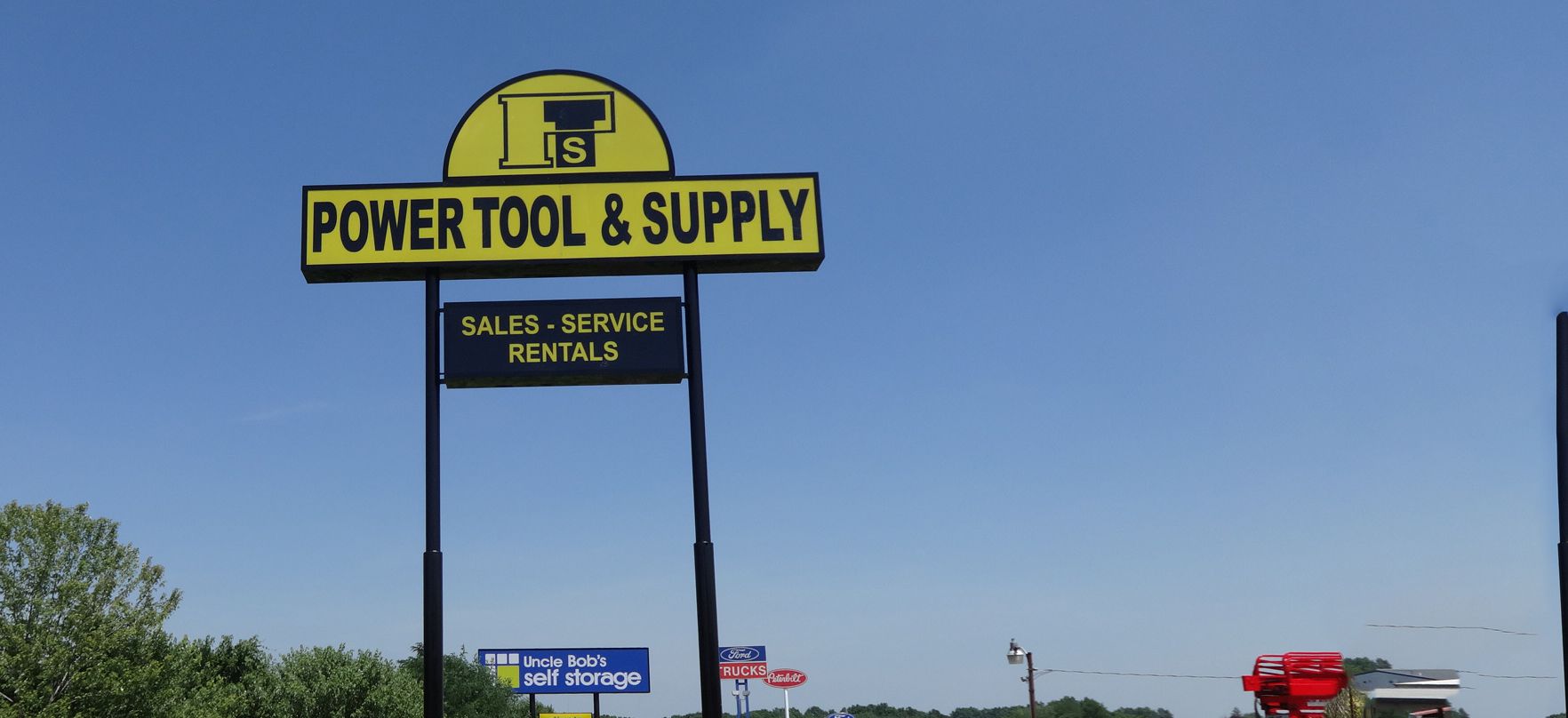 Yellow and black power tool and supply pole business sign