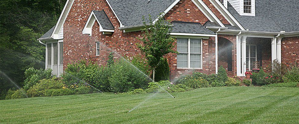 Several sprinklers in the front and side yard of a home