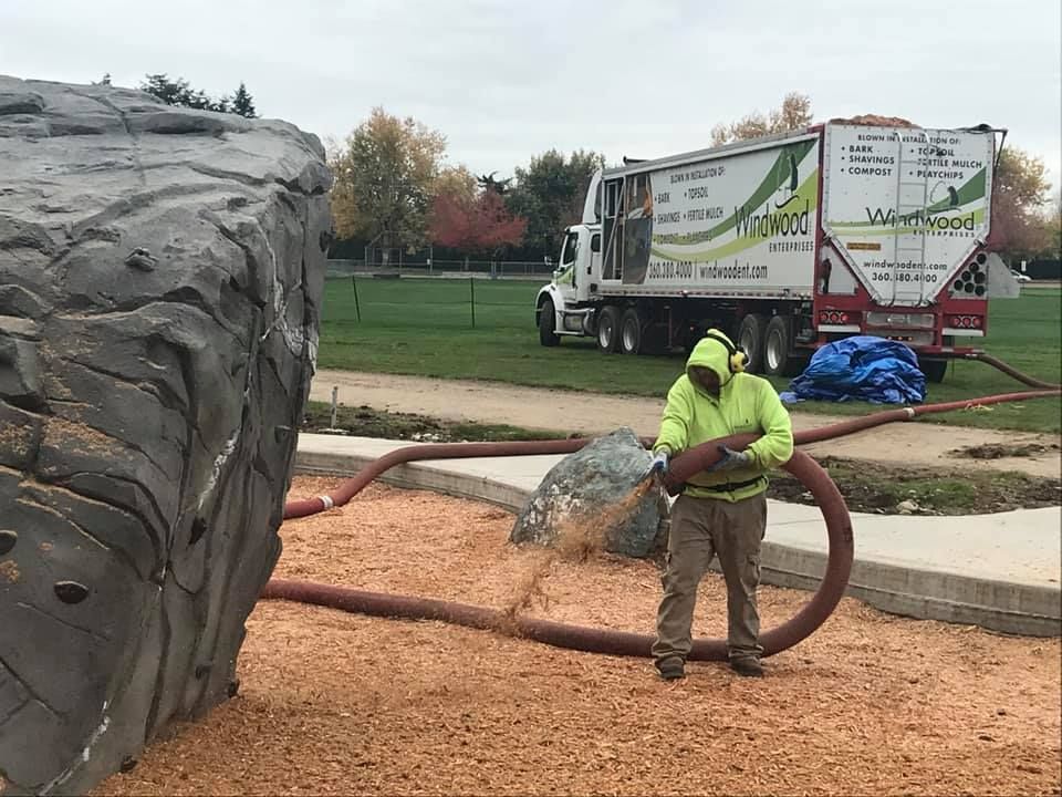 A man is standing in front of a truck with a hose attached to it.