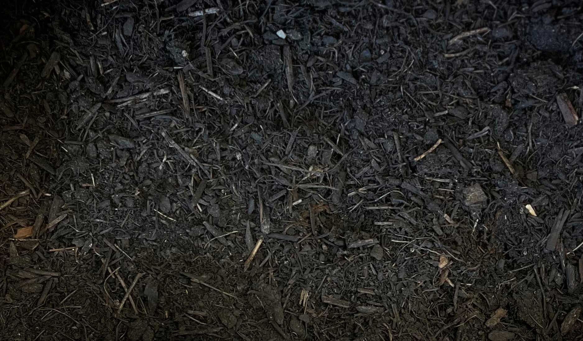 A close-up of a pile of black mulch/ compost.