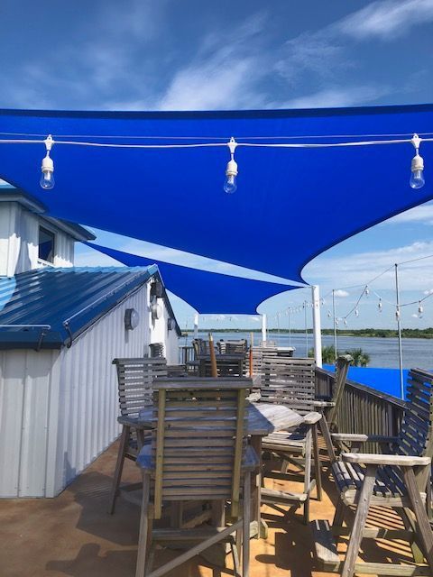 A patio with tables and chairs under a blue umbrella