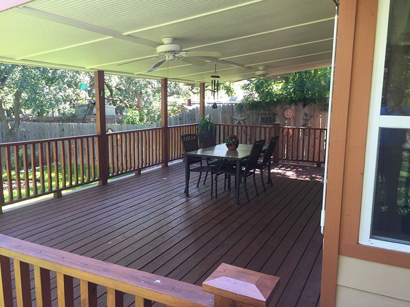 A large deck with a table and chairs and a ceiling fan.