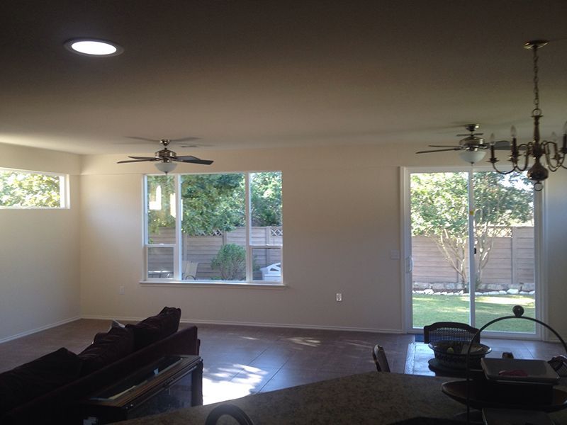 A living room with a ceiling fan and sliding glass doors