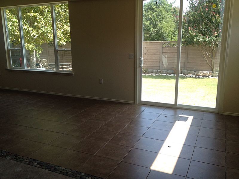 An empty living room with a sliding glass door leading to a backyard.