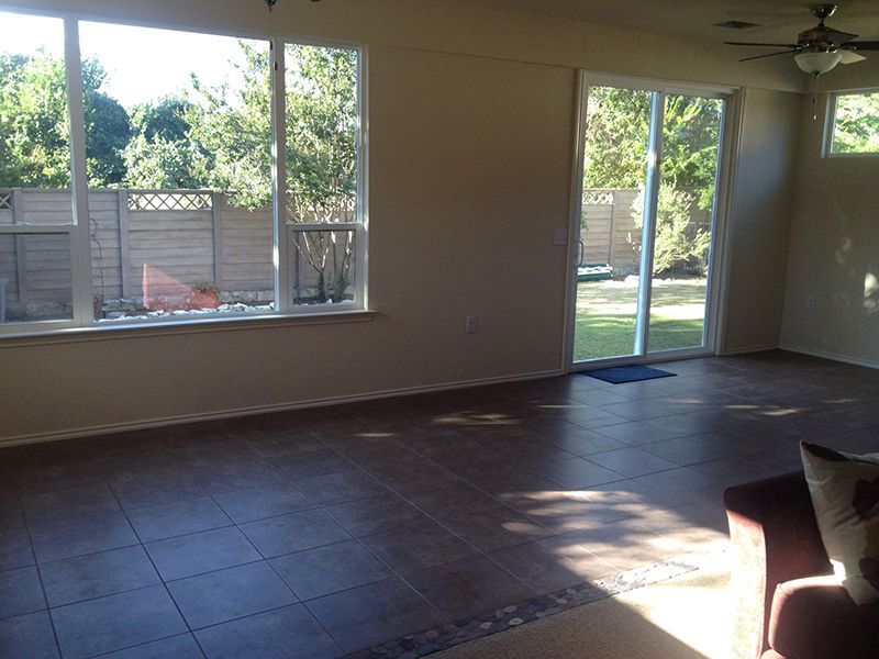 An empty living room with sliding glass doors and a ceiling fan