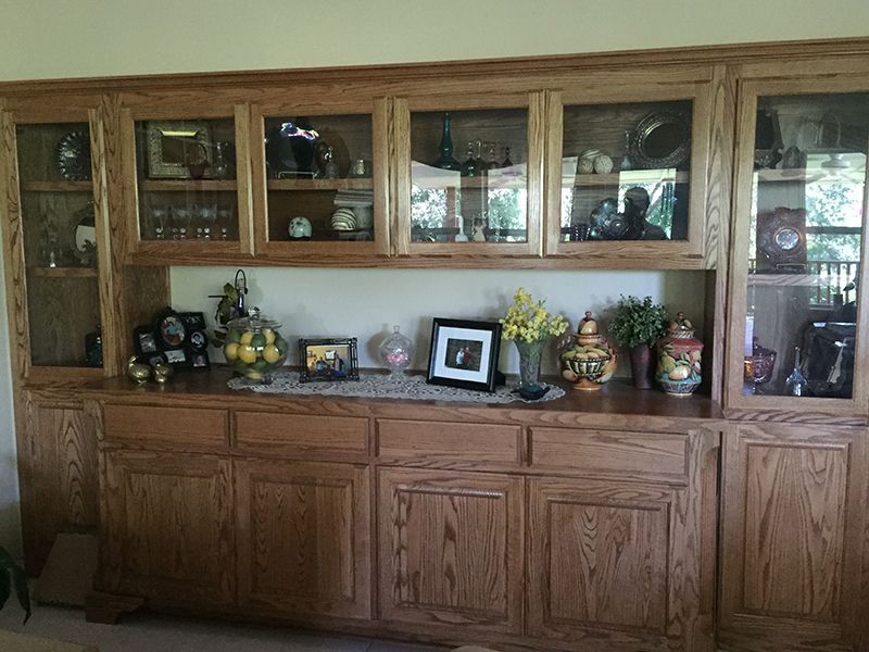 A large wooden cabinet with glass doors and drawers in a living room.