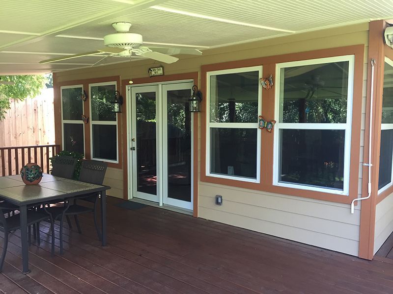 A screened in porch with a table and chairs and a ceiling fan.