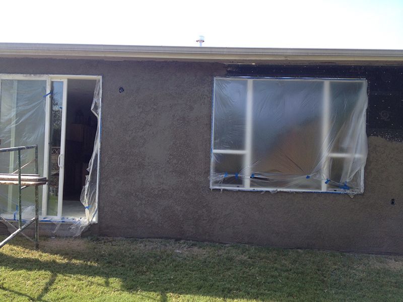 A house with a sliding glass door and a window covered in plastic.
