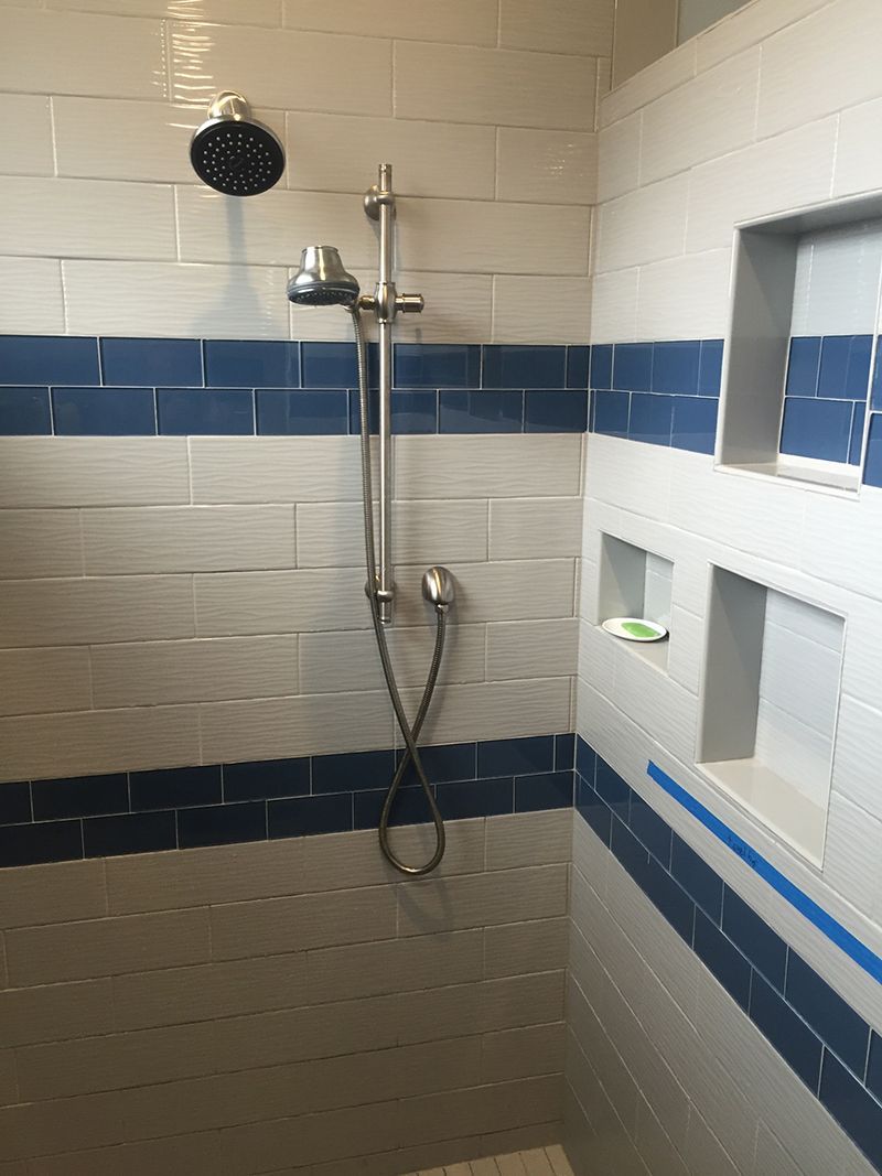A shower with blue and white tiles and a shower head
