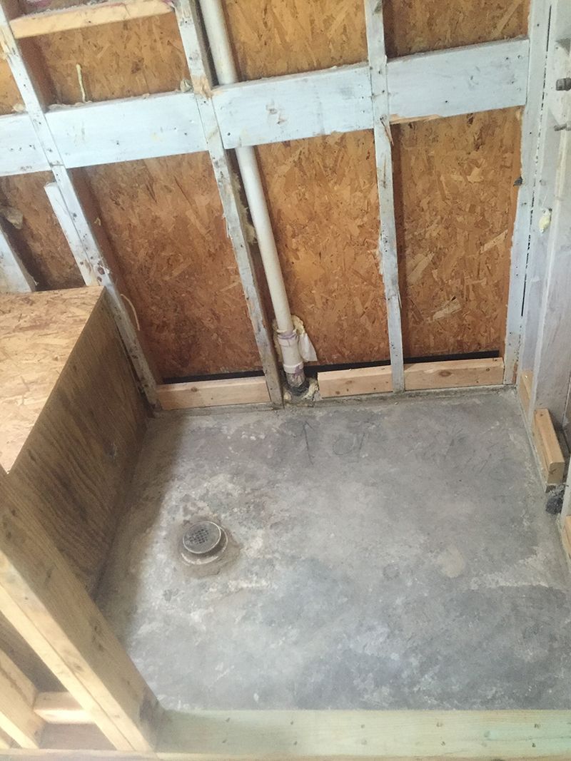 A bathroom under construction with a concrete floor and wooden walls.