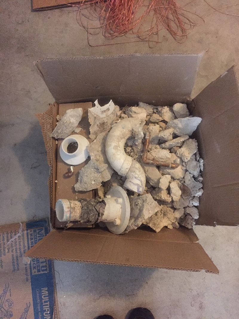 A cardboard box filled with pieces of plastic pipes
