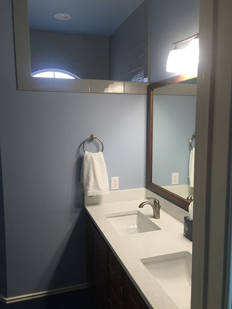 A bathroom with two sinks , a mirror and a window.