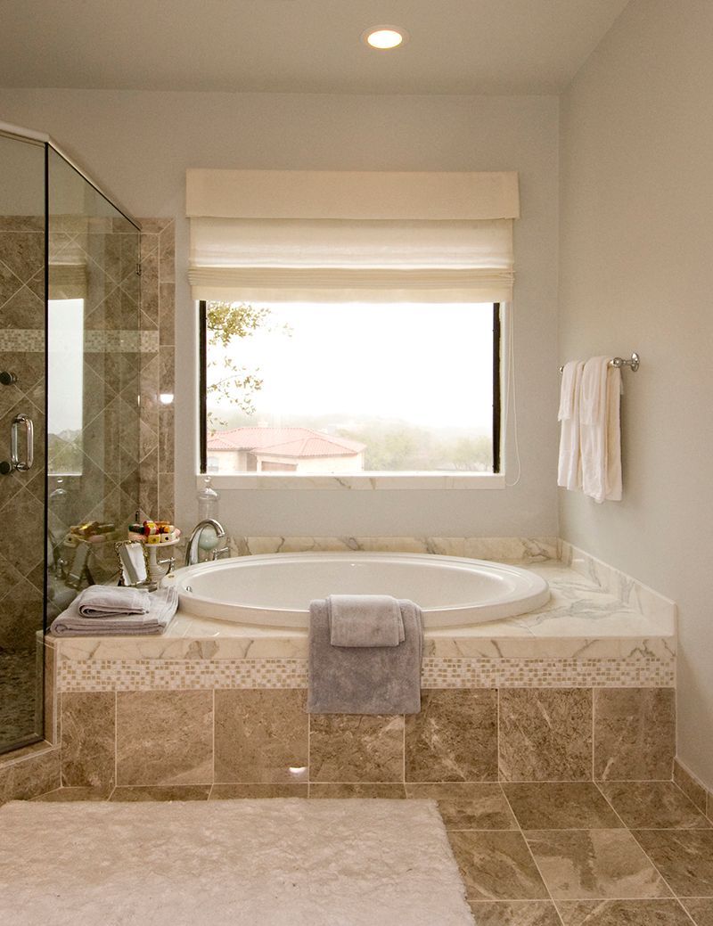A bathroom with a tub , shower , and window.