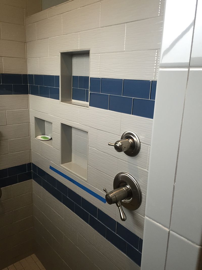 A bathroom with blue and white tiles and a shower head